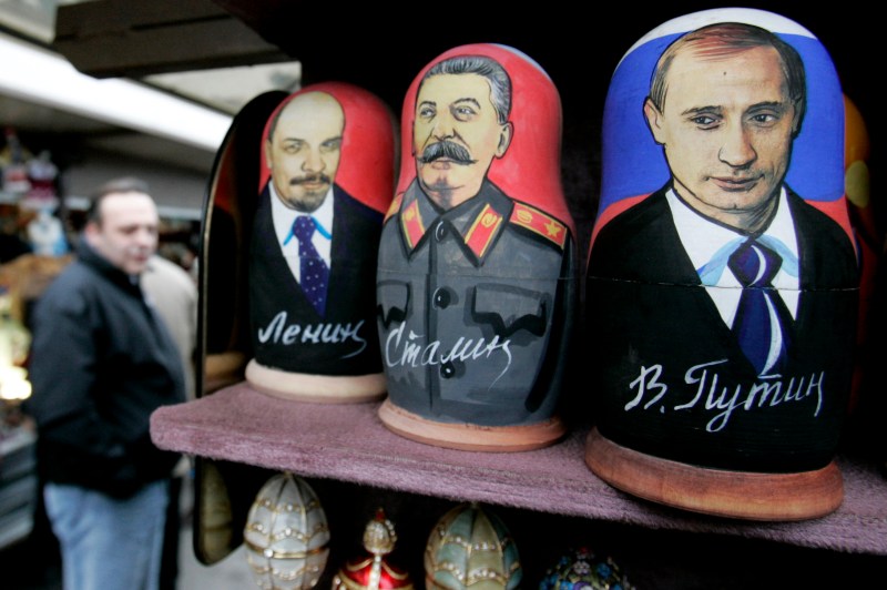 Customers walk past a shop with Russian matryoshka dolls decorated with portraits of Lenin, Stalin and Putin  at a market in the centre of St.Petersburg